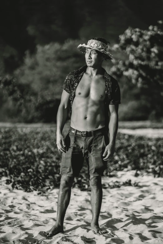 a man in shorts and a hat standing on sand