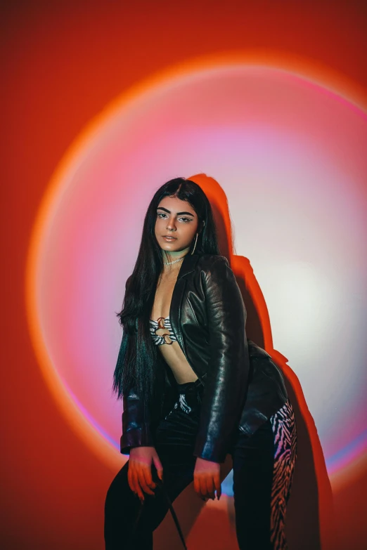 a women in black posing against a pink and orange circular background