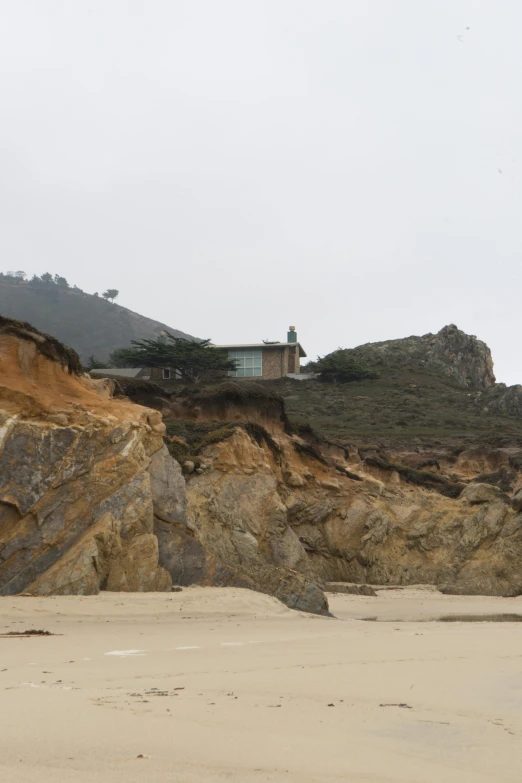 the building is on top of a cliff next to the beach
