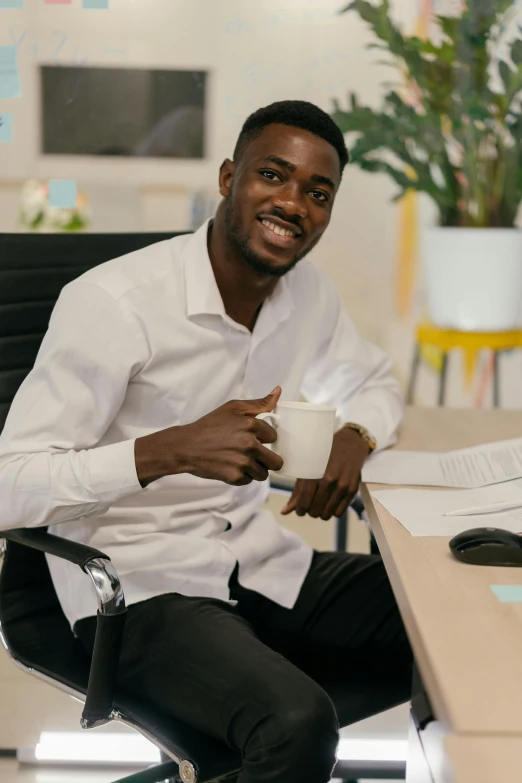 a man sitting at a desk with a coffee cup in his hand