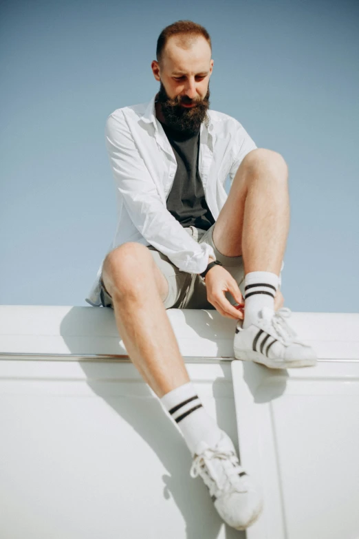 a man with a beard and socks sitting on a wall