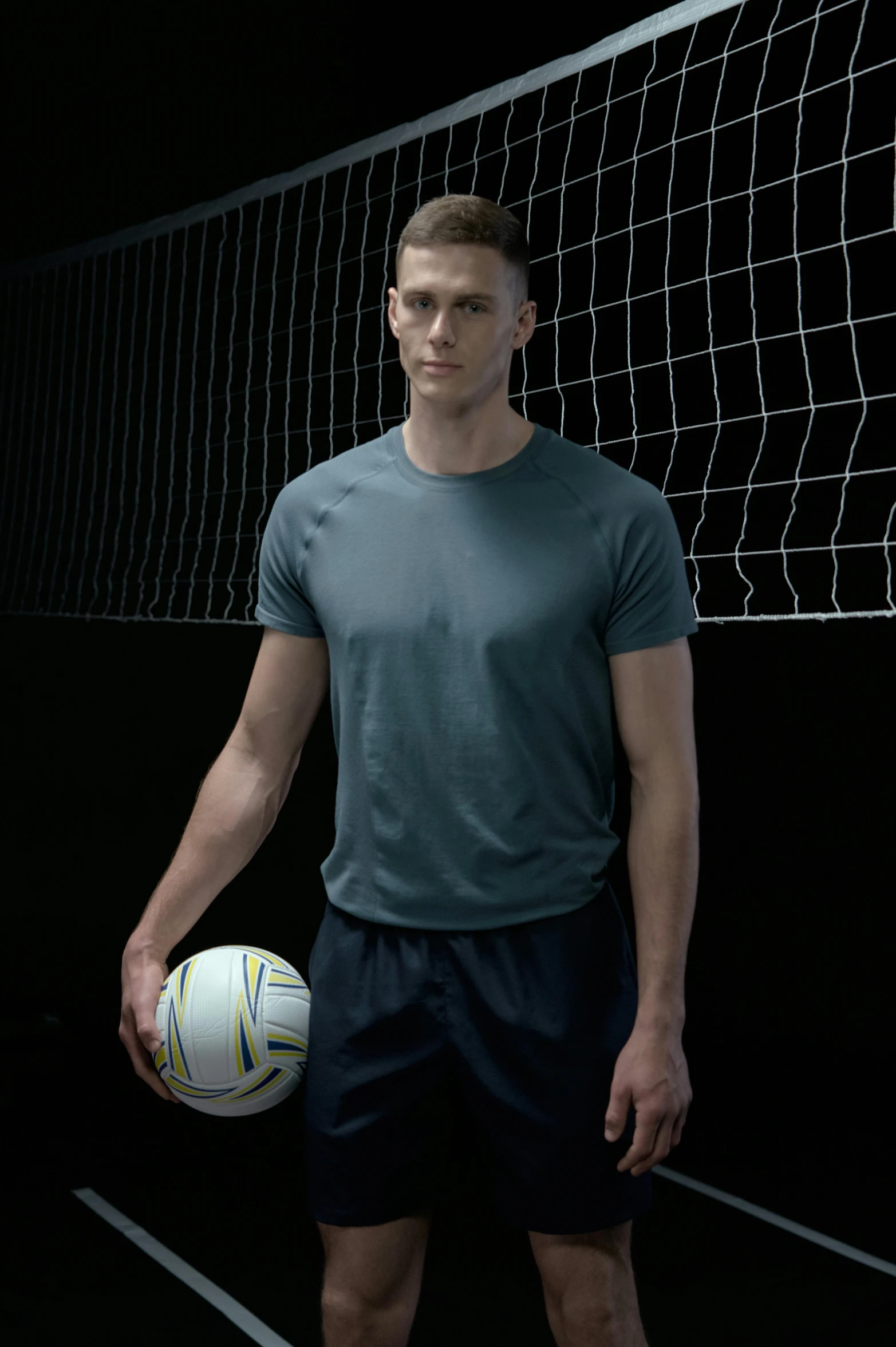 a man standing next to a volleyball on a court