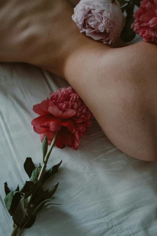 a person laying in bed with some flowers