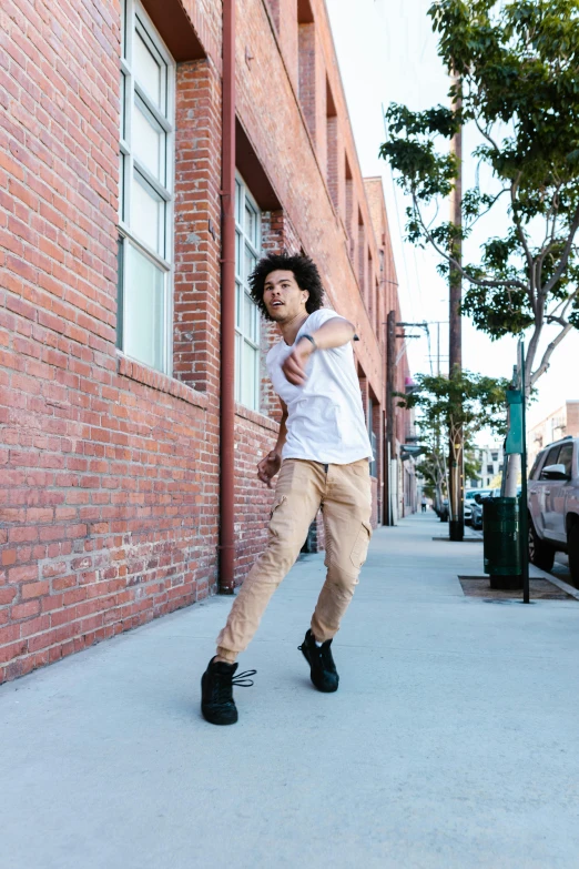 a guy in black boots leaning against a brick building