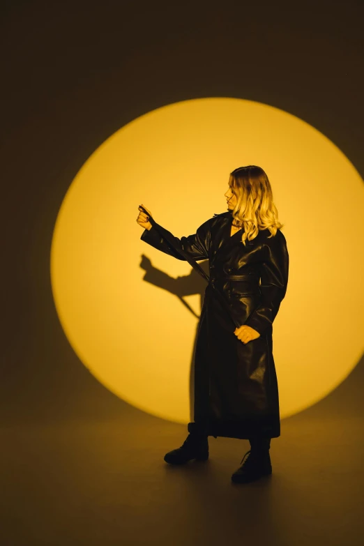 a woman in a black trench coat on a light background