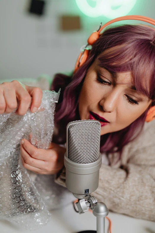 an image of a woman with headphones on while she is reading on a mic