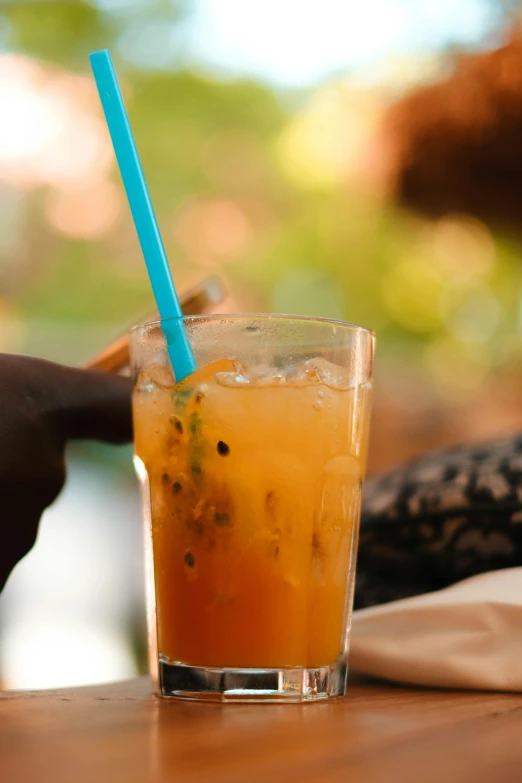 someone holds a blue straw above a beverage