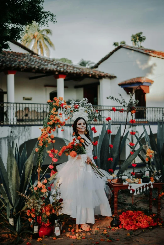 a woman dressed in a white wedding dress stands with flowers