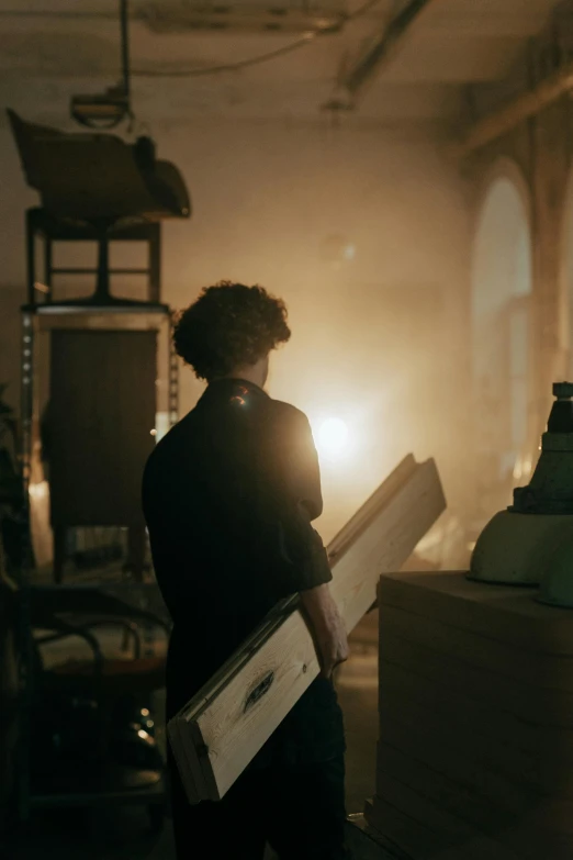 a young man is holding a giant block of wood