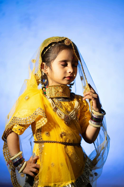 a girl dressed in yellow holds on to a veil