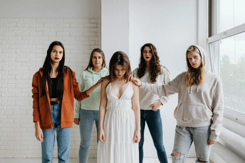 a group of girls pose for the camera in front of a brick wall