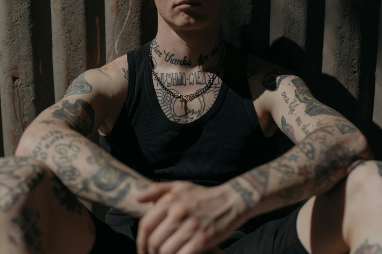 man sitting down looking at the camera with lots of tattoos on his hands