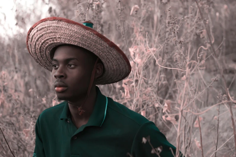 a man in a hat standing in some tall grass