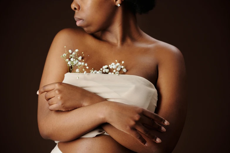 a young black woman wearing an ivory colored dress with flower garlands