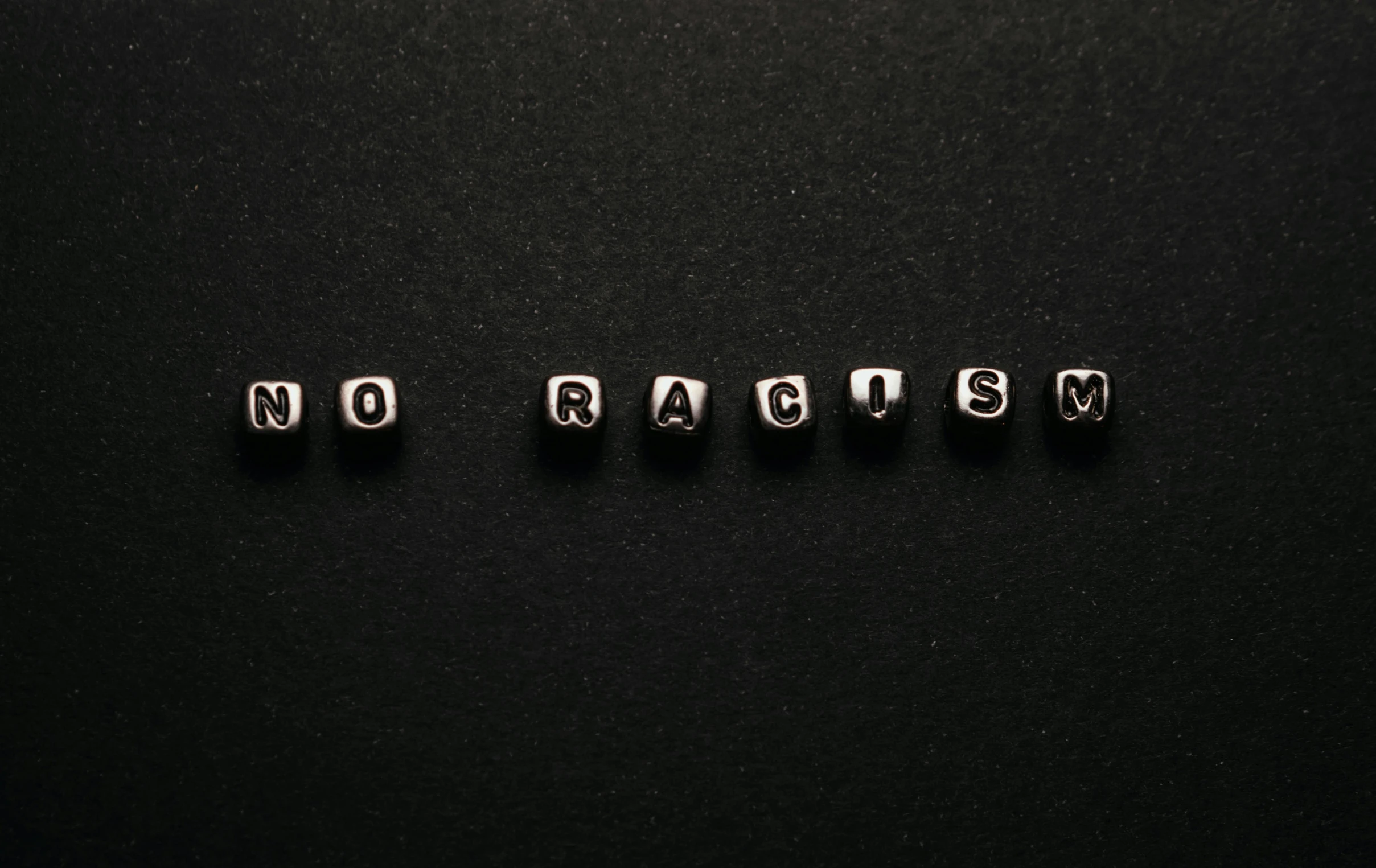 small letter cubes are laying in the same row on top of black surface