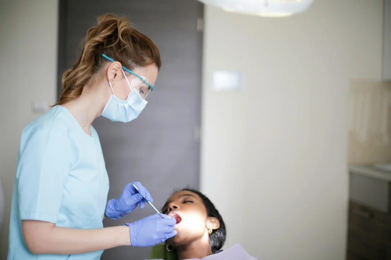 two dentists in gloves and masks hold instruments for an unseen patient