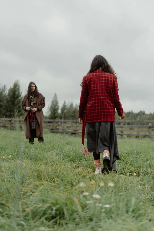 two women in plaid shirts and long coats in grass