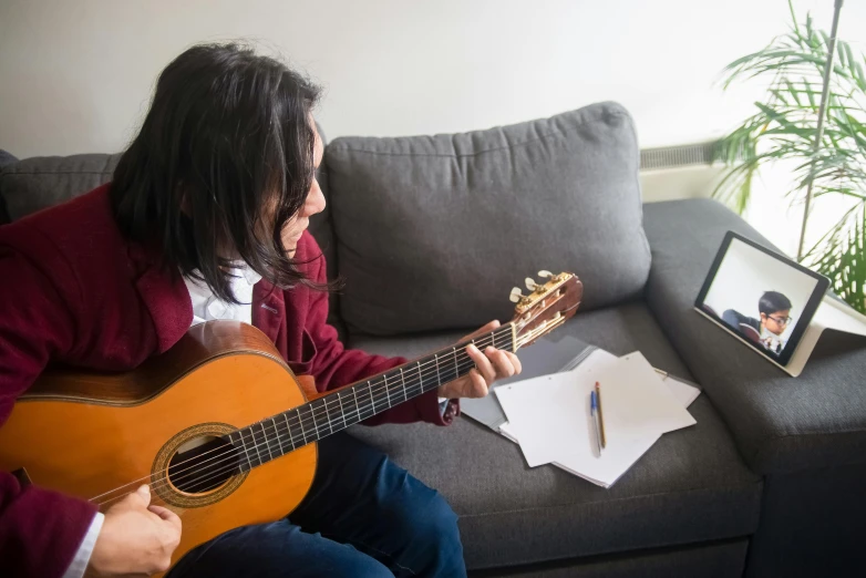 a person sitting on a couch with a guitar