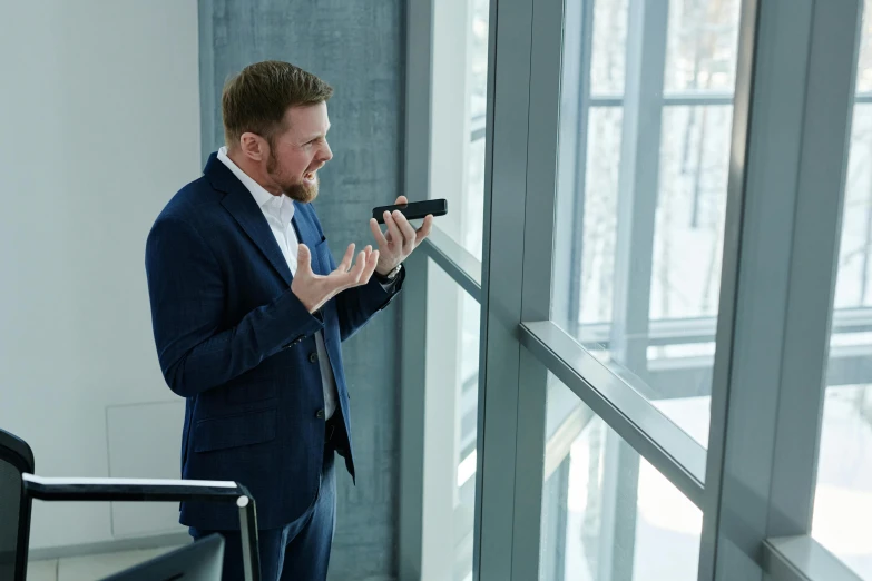 a man wearing a suit looks out the window at the rain