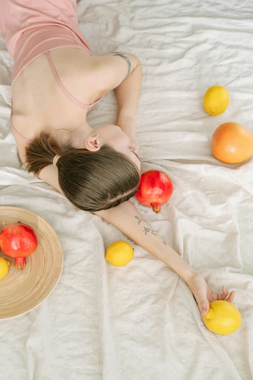 a young woman laying on top of a bed surrounded by fruit