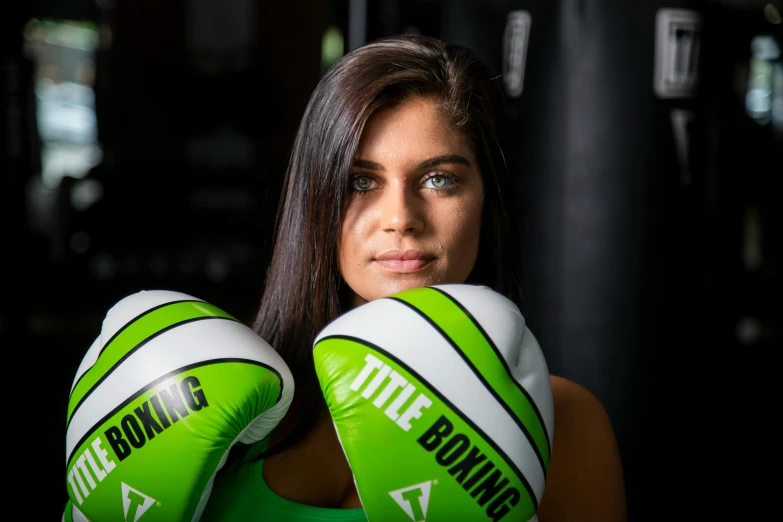 the beautiful woman in boxing gloves has her arms crossed and wears green