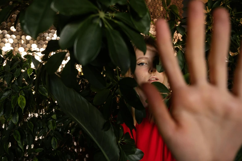 a girl in red posing behind a plant