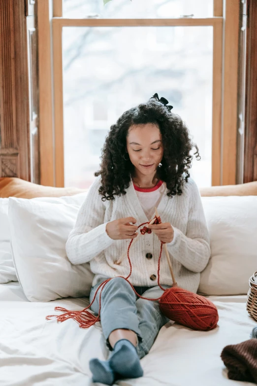 a woman is knitting on the bed