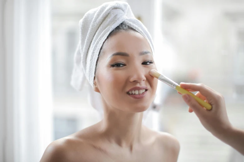 a woman wearing a towel applying her makeup