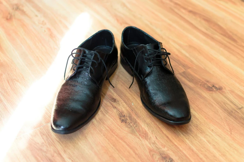 a pair of black shoes are laying on a hard wood floor