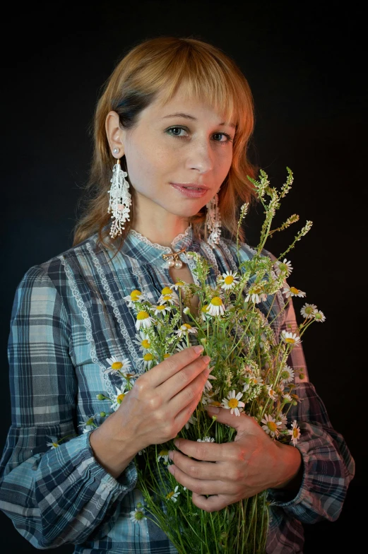 a woman holding some flowers and looking at the camera