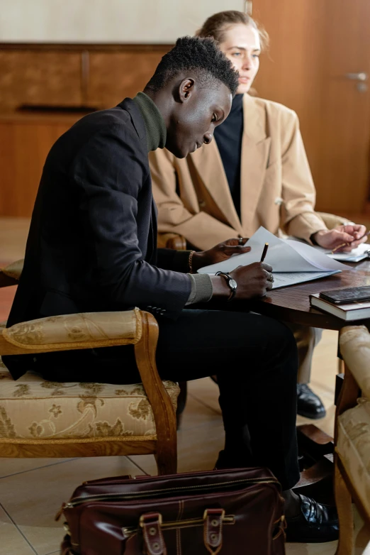 two people sitting at a table with some papers