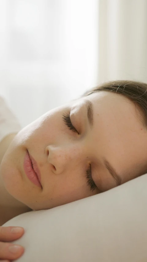 the woman is asleep on her stomach on a white comforter