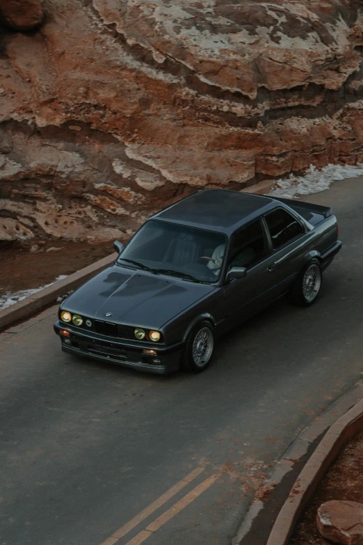 a car that is driving down the road by some cliffs