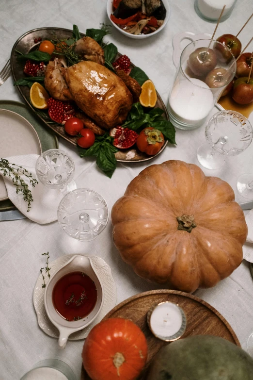 a thanksgiving turkey with fresh fruit and other vegetables is sitting on a white tablecloth