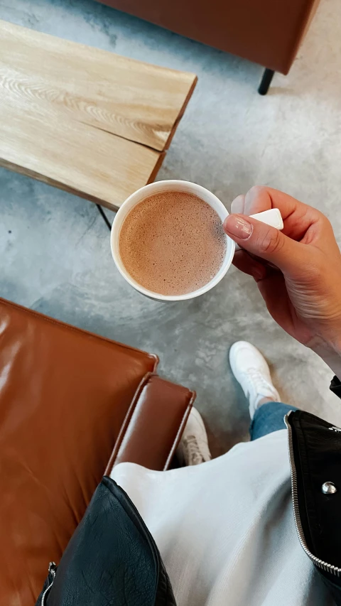 person sitting down holding up a small cup of coffee