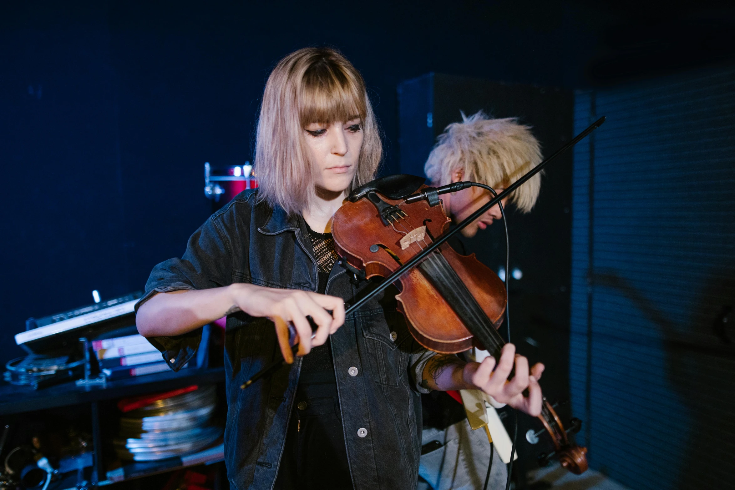 a woman playing a violin in front of a microphone