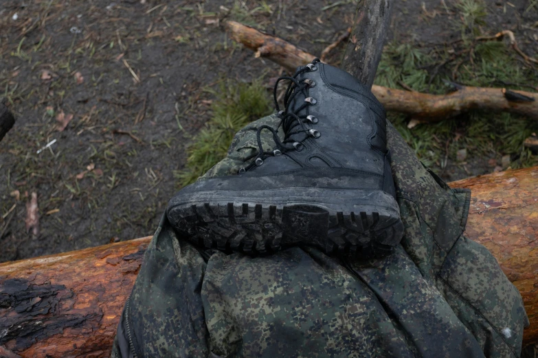 a pair of black high top boots standing on the forest floor