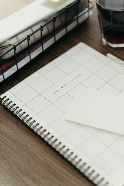 a notebook next to glasses and some pens