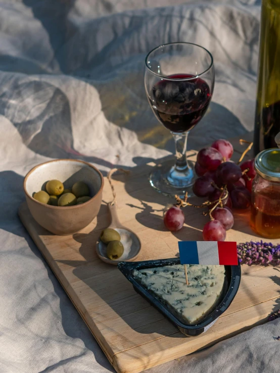 the wine bottle, cheese, gs, and nuts are on a tray