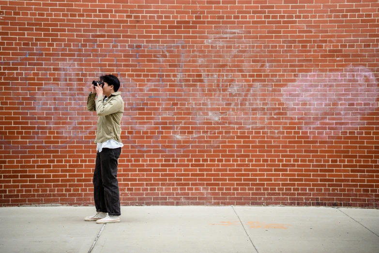 a woman standing in front of a brick wall talking on a cell phone