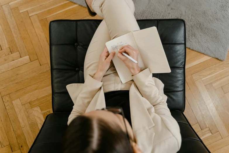 a person sitting on top of a chair with a pen and paper