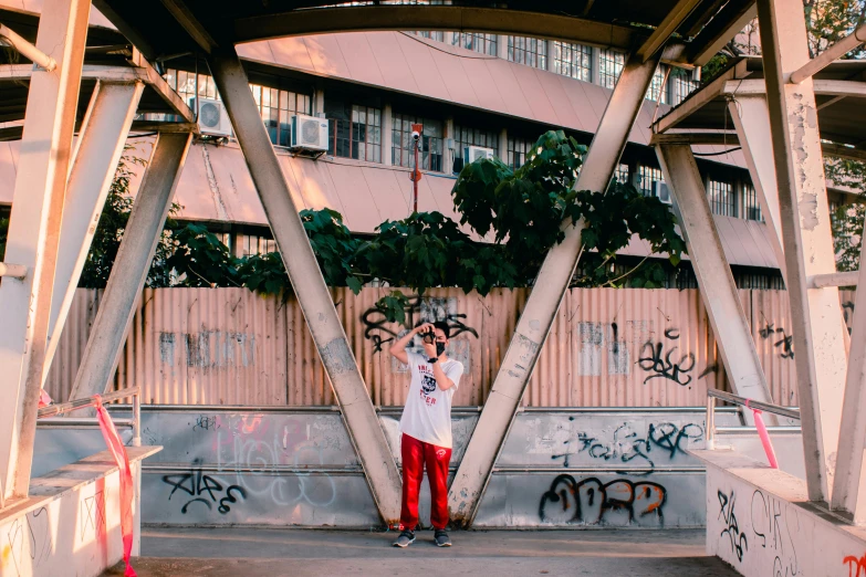 a young man taking a picture on his cell phone under a bridge