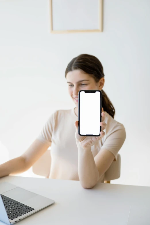 a woman in a beige sweater looking at her cell phone