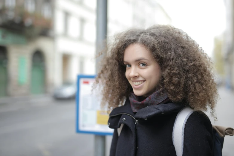 a beautiful young woman standing next to a sign