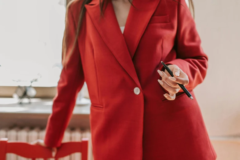 a woman in red suit and heels with a pen