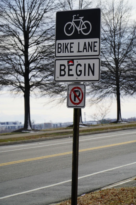 a sign for bikes on a pole in front of some trees