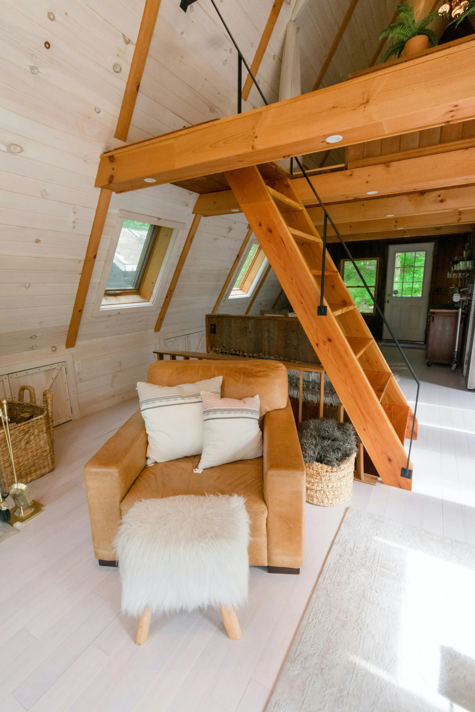 a loft sitting room with open staircase and loft bed in background