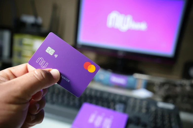 a person is holding up a purple credit card