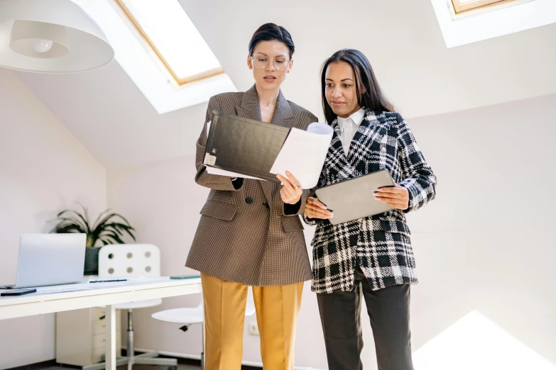 two women with notebooks, in a room