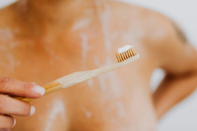 a woman holding a toothbrush with the toothpaste on her face